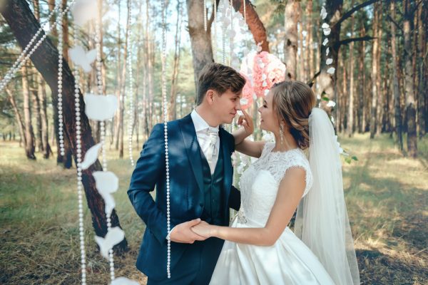 The bride and groom in wedding dresses on natural background.The stunning young couple is incredibly happy. Wedding day. Newlyweds are walking through the forest. Lovers and happy people.